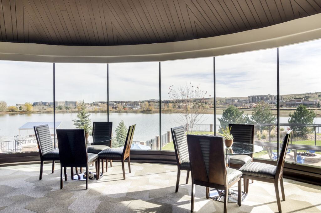Clubhouse lounge with table and chairs, panoramic view of the lake