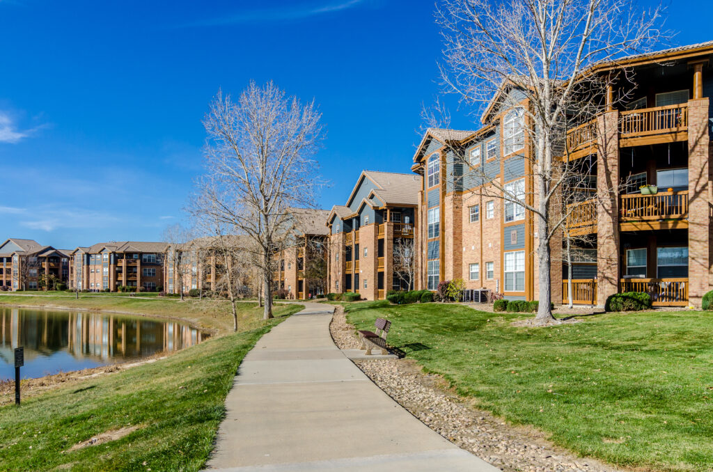 Building exteriors showing balconies and trees, walking path by the water