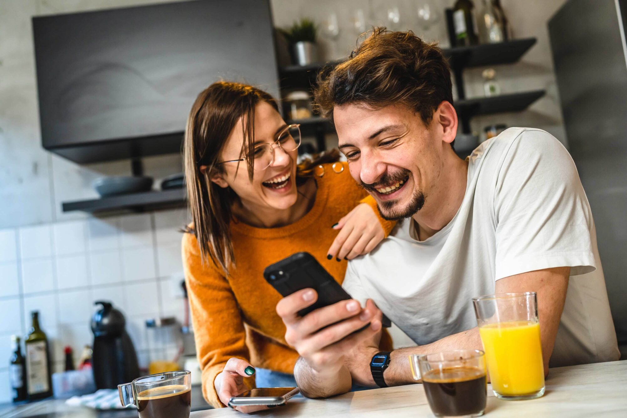 Happy young couple looking at their phones and laughing